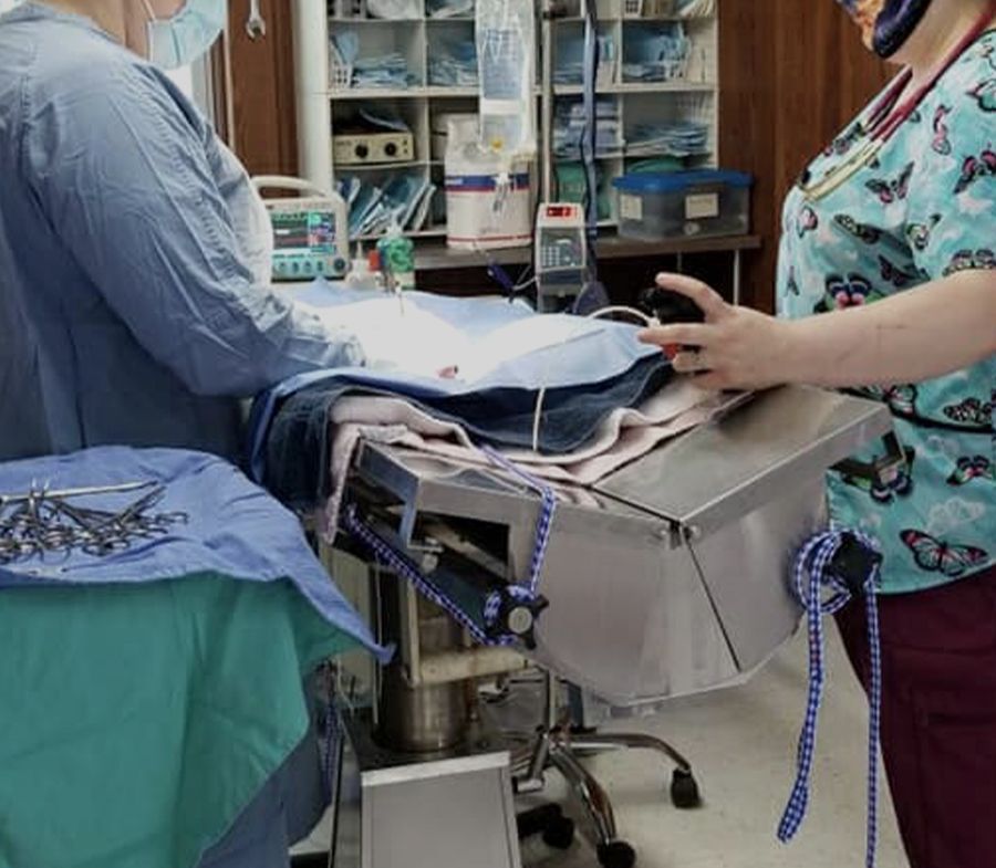 Two medical professionals attending to a patient in a surgical environment.